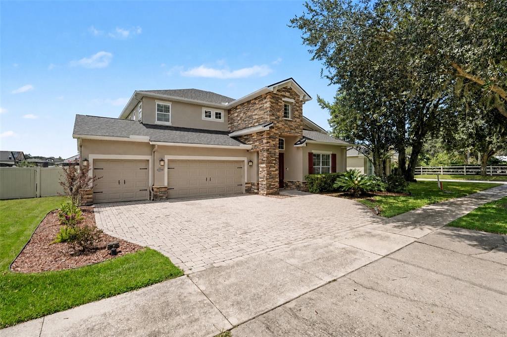 A two-story house with a stone facade, a three-car garage, and a paved driveway — 2605 RED FERN DRIVE, DOVER, FL