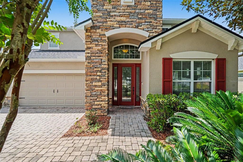 A stone-accented house exterior features a red front door, a garage, and a paved driveway — 2605 RED FERN DRIVE, DOVER, FL
