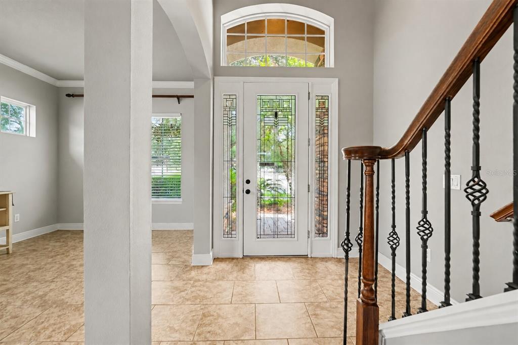 A bright entryway features tiled floors, a decorative glass front door, and a wooden staircase — 2605 RED FERN DRIVE, DOVER, FL