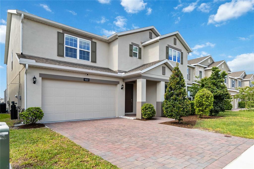 A two-story suburban house features a beige stucco exterior, a paved driveway, and a garage — 5022 DOWN COURT, ST CLOUD, FL