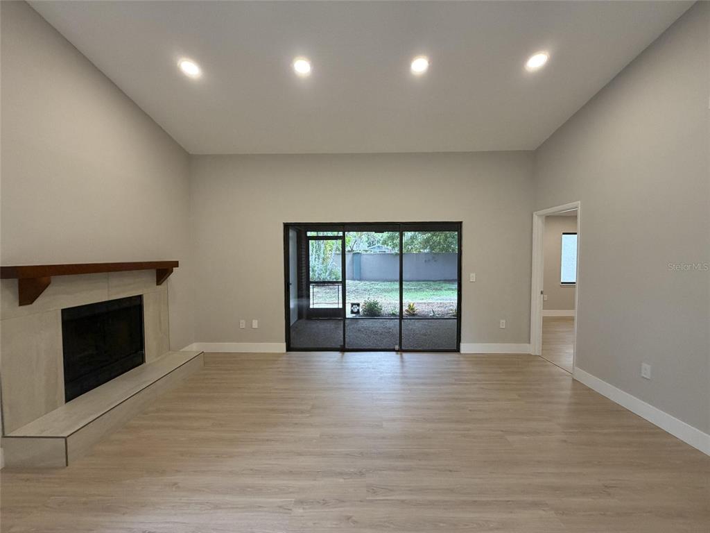 A living room features light wood-look flooring, a fireplace with a wood mantel, and sliding doors — 971 SUNRIDGE DRIVE UNIT 110, SARASOTA, FL