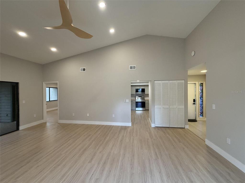 A spacious living area features light wood-look flooring, vaulted ceilings, and a ceiling fan — 971 SUNRIDGE DRIVE UNIT 110, SARASOTA, FL