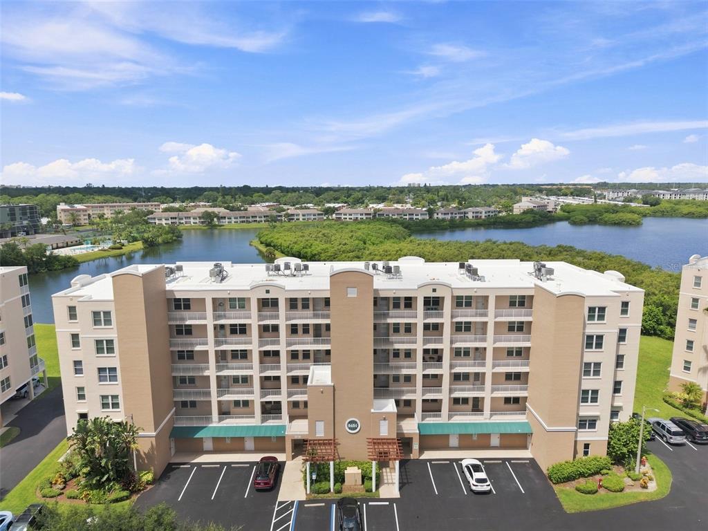 An aerial view shows a multi-story tan apartment building with balconies overlooking a lake — 6450 SHORELINE DRIVE UNIT 9306, SEMINOLE, FL