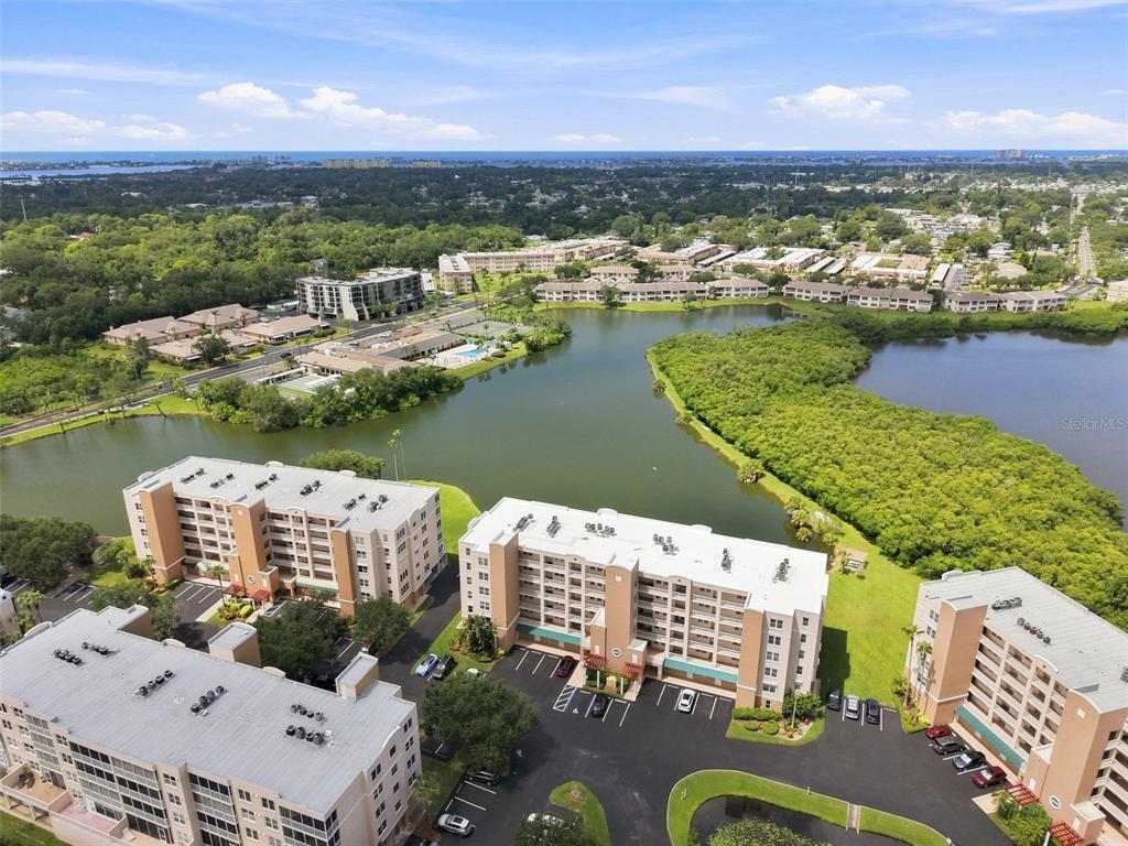 An aerial view shows several multi-story apartment buildings surrounding a large lake and green space — 6450 SHORELINE DRIVE UNIT 9306, SEMINOLE, FL