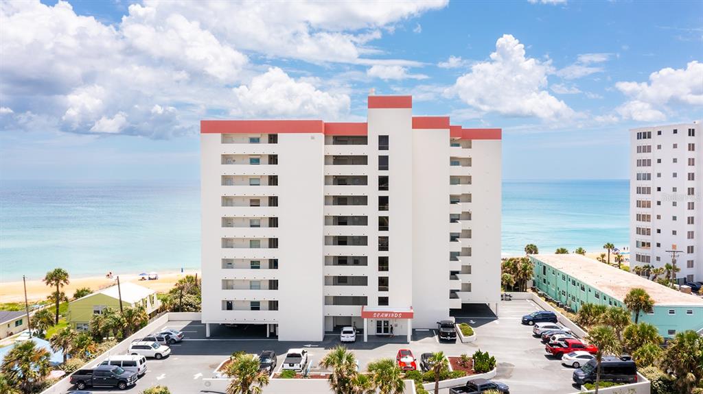 An aerial view shows the exterior of a white multi-story beachfront condominium building — 1183 OCEAN SHORE BOULEVARD UNIT 604, ORMOND BEACH, FL