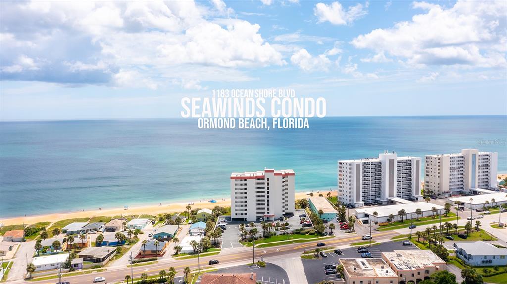 An aerial view shows a multi-story condominium building located directly on a sandy beach — 1183 OCEAN SHORE BOULEVARD UNIT 604, ORMOND BEACH, FL