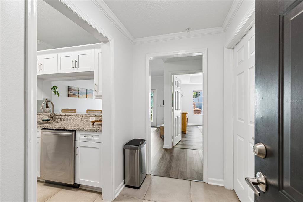 A kitchen with white cabinets, granite countertops, and stainless steel appliances leads to a hallway — 800 S DAKOTA AVENUE UNIT 237, TAMPA, FL
