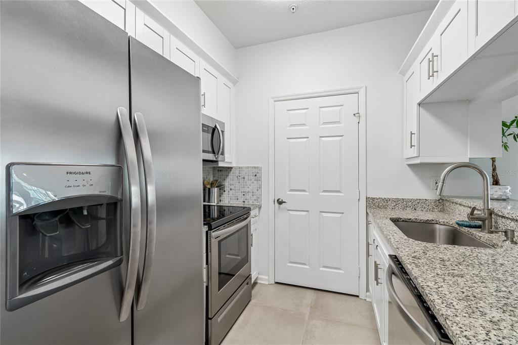 A galley kitchen features white cabinets, granite countertops, stainless steel appliances, and a central door — 800 S DAKOTA AVENUE UNIT 237, TAMPA, FL