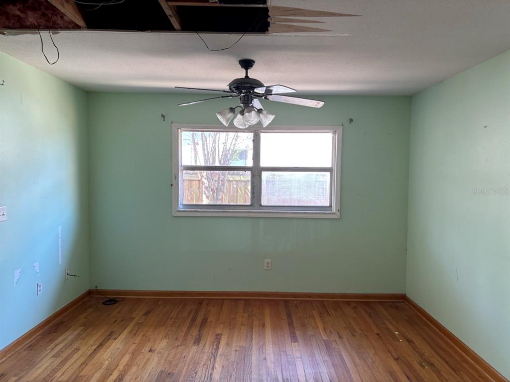 An empty room with light green walls, hardwood floors, a ceiling fan, and damaged ceiling — 4604 RIDGE POINT, TAMPA, FL