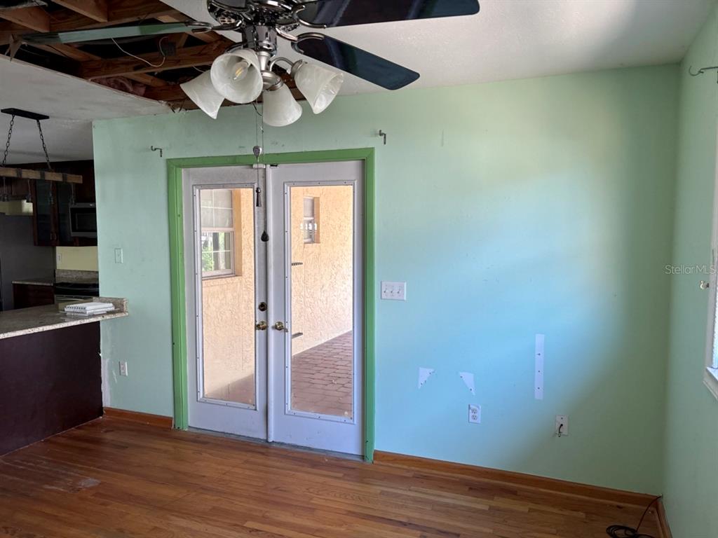 A room with light green walls, wood flooring, a ceiling fan, and double glass doors — 4604 RIDGE POINT, TAMPA, FL