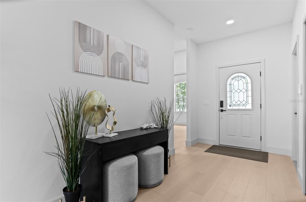 A bright entryway features light wood floors, a black console table, and abstract wall art — 22836 MARSH WREN DRIVE, LAND O LAKES, FL