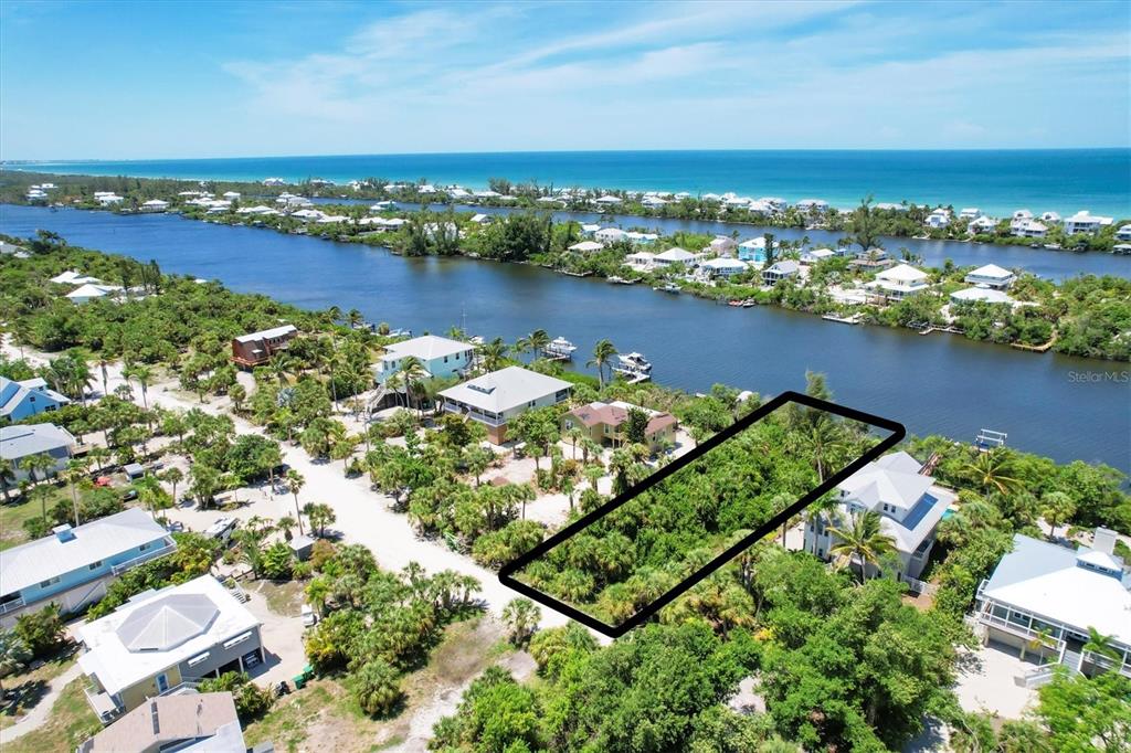 An aerial view shows a vacant, rectangular lot surrounded by tropical vegetation and nearby houses — 211 KETTLE HARBOR DRIVE, PLACIDA, FL
