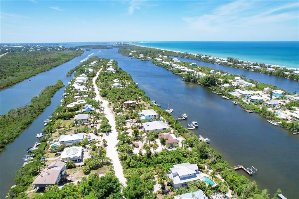 An aerial view shows houses nestled among lush vegetation along a narrow, water-bordered peninsula — 211 KETTLE HARBOR DRIVE, PLACIDA, FL