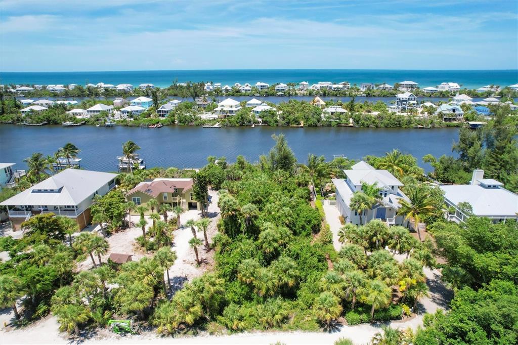 An aerial view shows houses situated between a narrow waterway and a sandy beach — 211 KETTLE HARBOR DRIVE, PLACIDA, FL
