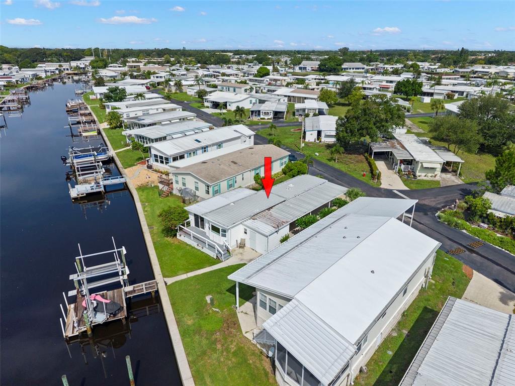 A wooden boat dock with a covered jet ski sits along a canal with grass — 436 MOUNT OAK AVENUE NE UNIT 747, ST PETERSBURG, FL