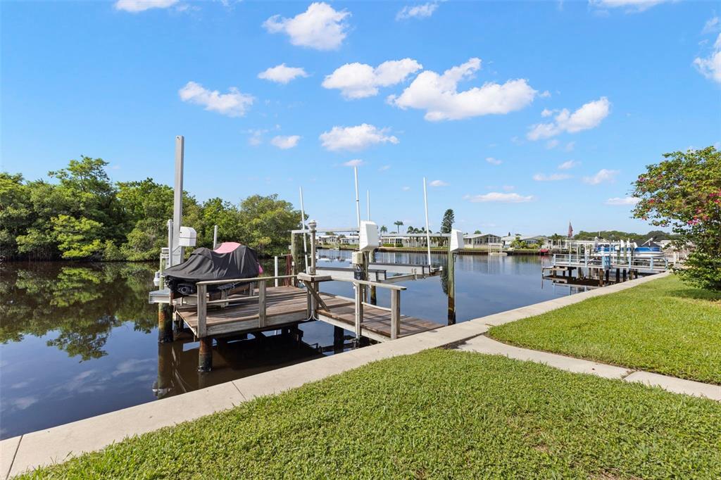 A wooden dock overlooks a calm canal lined with lush green trees and palm trees — 436 MOUNT OAK AVENUE NE UNIT 747, ST PETERSBURG, FL