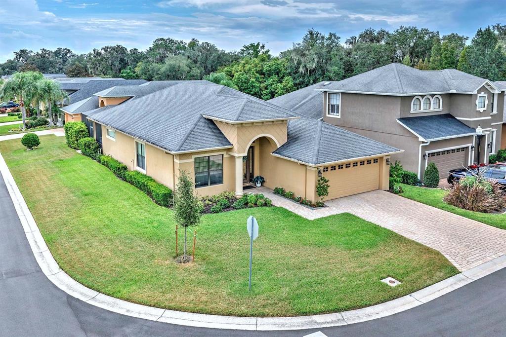 An exterior view of a tan, single-story suburban house with a gray roof and driveway — 904 CHRISTINA CHASE LANE, LAKELAND, FL