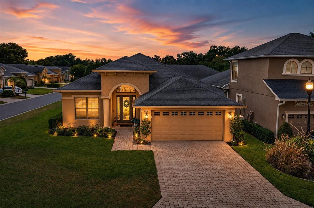 An exterior view of a single-story suburban house with a paved driveway at sunset — 904 CHRISTINA CHASE LANE, LAKELAND, FL