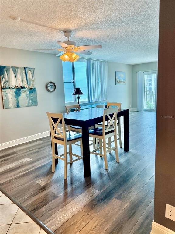 A dining area features a dark wood table with four white chairs on wood flooring — 1480 GULF BOULEVARD UNIT 607, CLEARWATER BEACH, FL