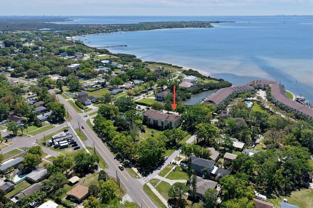 An aerial view shows a multi-story residential building near a coastal bay and road — 108 BRENT CIRCLE, OLDSMAR, FL