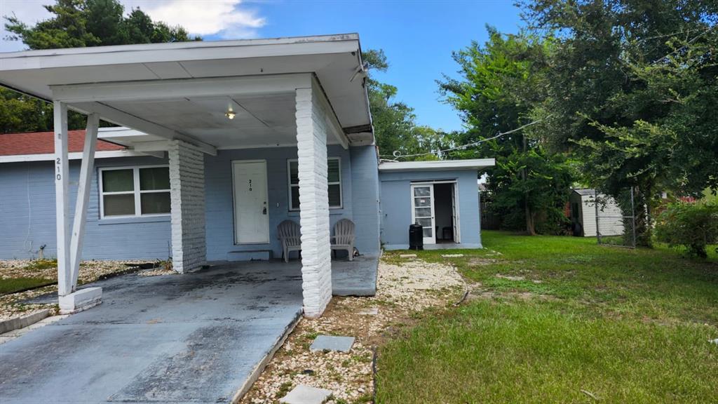 A light blue house with a carport, white brick pillars, and a small backyard — 210 FRANCIS PARKMAN PLACE, DAYTONA BEACH, FL