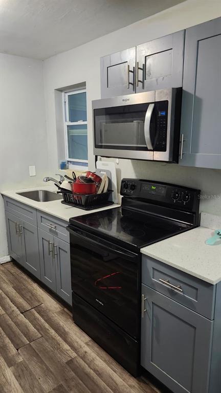 A kitchen features gray cabinets, a stainless steel microwave, a black stove, and light countertops — 210 FRANCIS PARKMAN PLACE, DAYTONA BEACH, FL