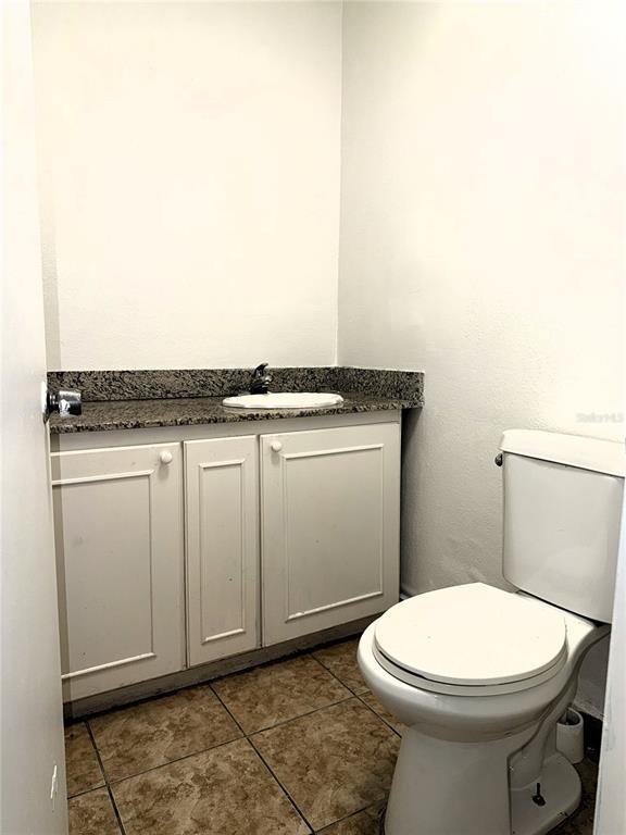 A small bathroom features a white vanity with a granite countertop and a toilet — 8421 S ORANGE BLOSSOM TRAIL UNIT 228, ORLANDO, FL