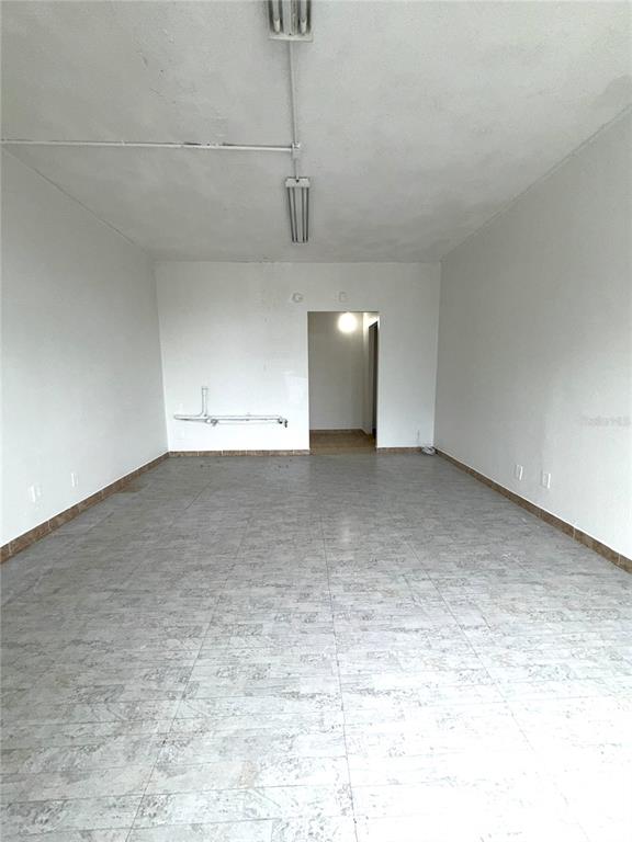 An empty commercial space features white walls, a tiled floor, and exposed ceiling light fixtures — 8421 S ORANGE BLOSSOM TRAIL UNIT 228, ORLANDO, FL