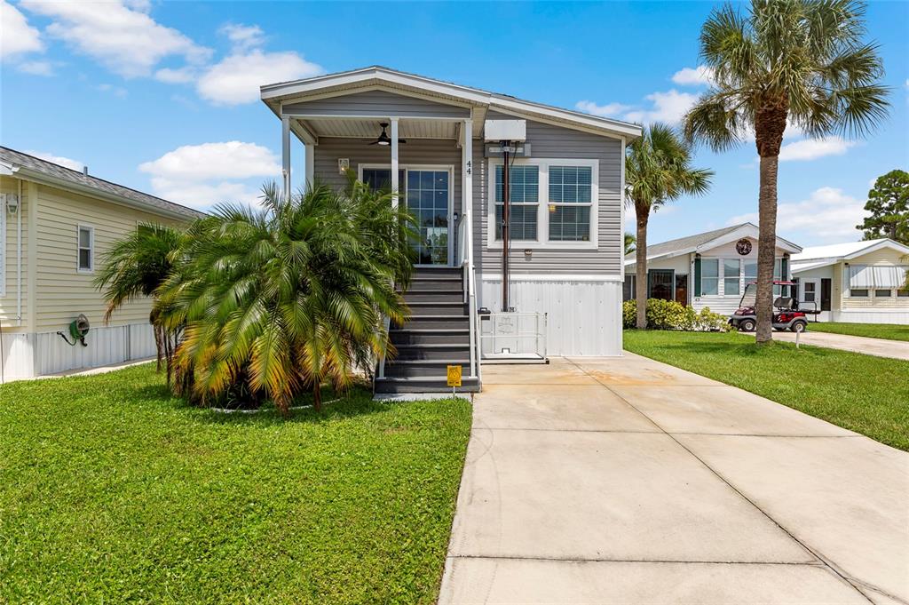 A gray manufactured home with a front porch, stairs, and a concrete driveway — 44 CROWN POINT DRIVE, NOKOMIS, FL