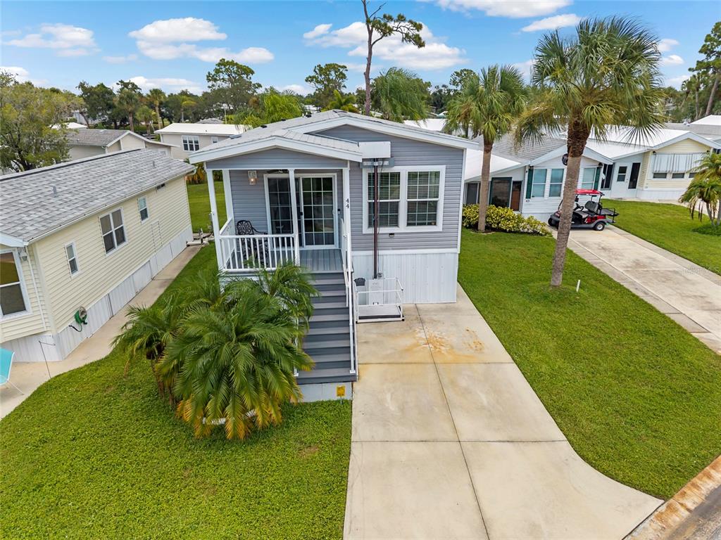 A light gray manufactured home with a front porch, stairs, and a concrete driveway — 44 CROWN POINT DRIVE, NOKOMIS, FL