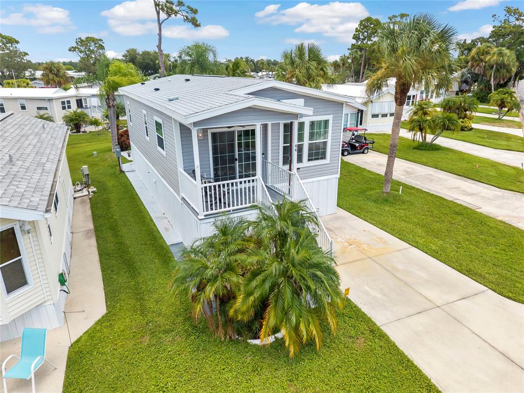 An elevated manufactured home with light gray siding, a front porch, and a concrete driveway — 44 CROWN POINT DRIVE, NOKOMIS, FL