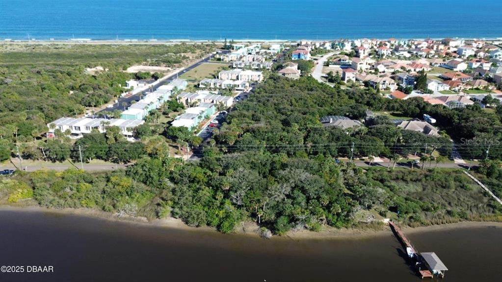 An aerial view shows a coastal neighborhood with houses, dense vegetation, and a private dock — 3780 JOHN ANDERSON DRIVE, ORMOND BEACH, FL