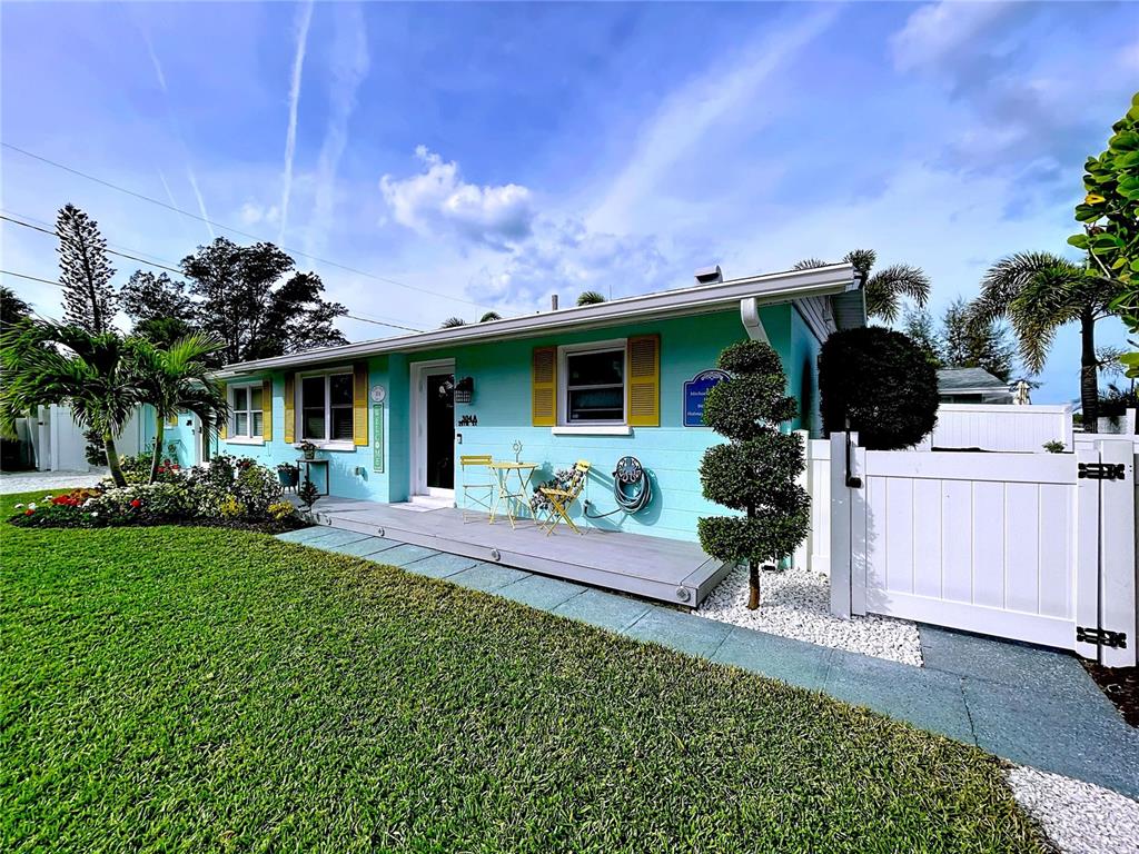 A turquoise single-story house with yellow shutters, a wooden deck, and a white fence — 304 29TH STREET UNIT A, HOLMES BEACH, FL