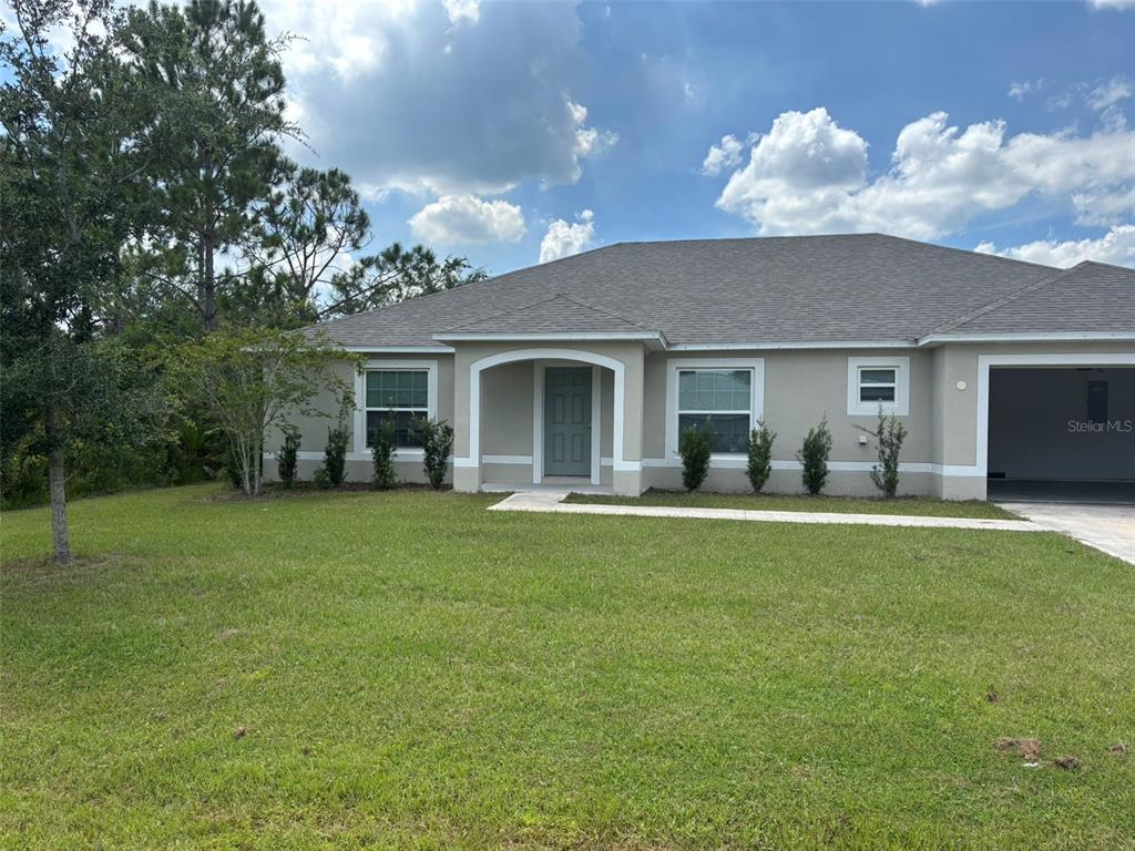 A single-story house with a beige stucco exterior, a gray roof, and a two-car garage — 15 LAMOYNE LANE, PALM COAST, FL