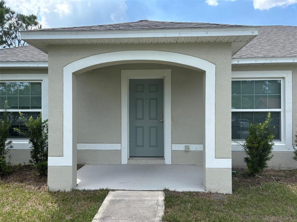 The exterior view shows a beige house with a covered entryway and a gray door — 15 LAMOYNE LANE, PALM COAST, FL