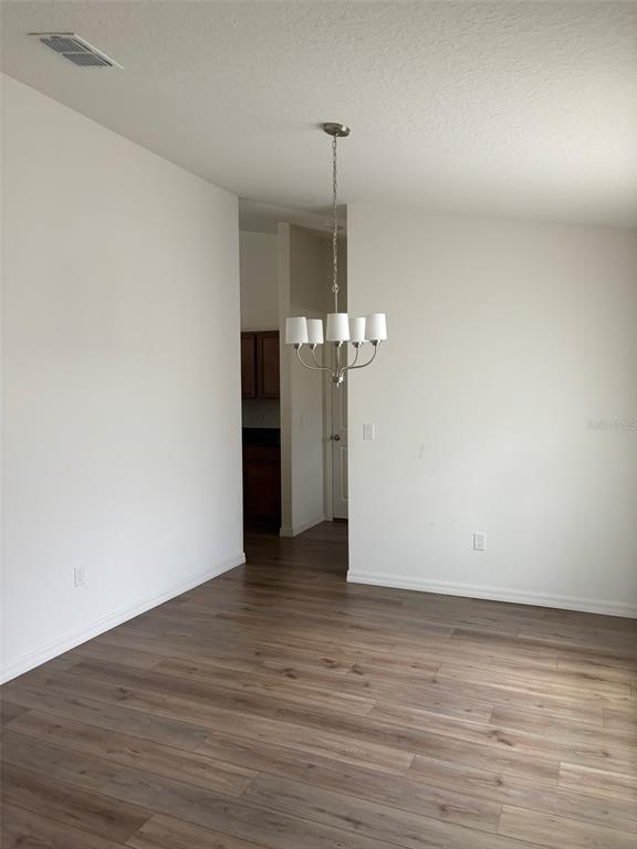 An empty dining area features wood-look flooring, white walls, and a five-light chandelier — 15 LAMOYNE LANE, PALM COAST, FL