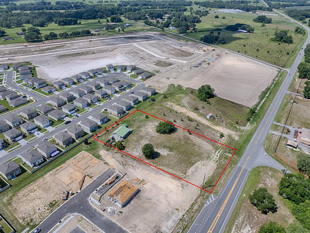 An aerial view shows a house on a large lot outlined in red near suburban development — 1891 S US 301, SUMTERVILLE, FL