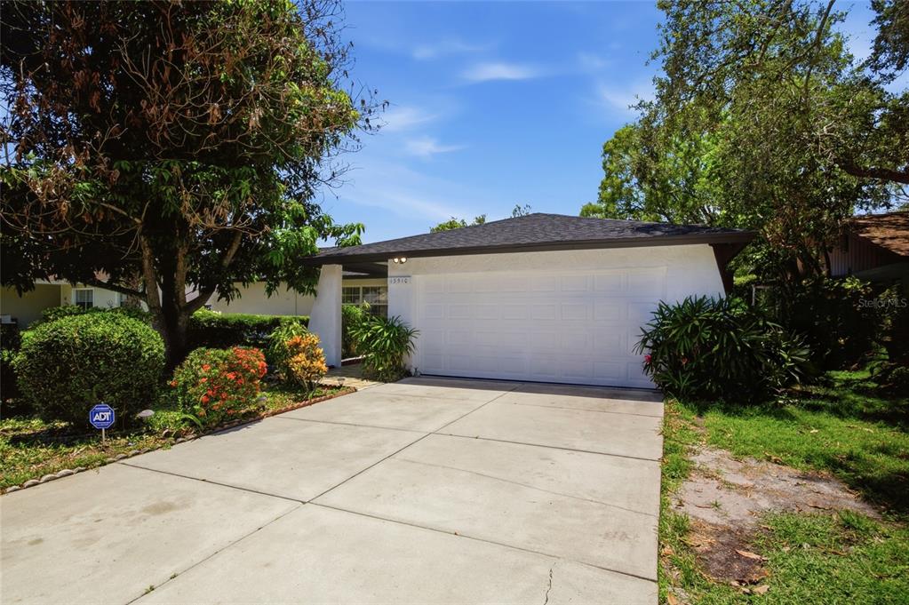 A single-story house with a white exterior, a two-car garage, and a concrete driveway — 13510 CAPITOL DRIVE, TAMPA, FL