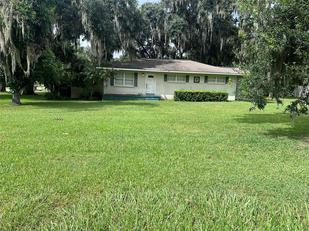 A single-story house with a light-colored exterior sits behind a large, grassy lawn — 315 W CARTER ROAD, LAKELAND, FL