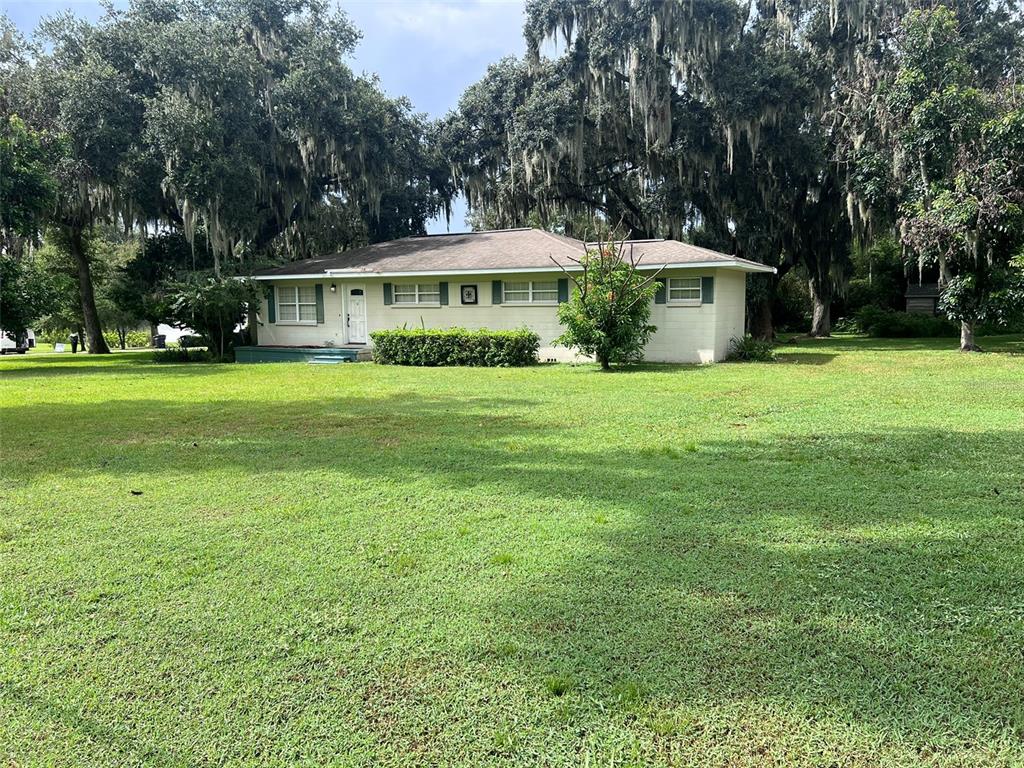 A single-story house with light-colored siding sits on a large grassy lot under mature trees — 315 W CARTER ROAD, LAKELAND, FL