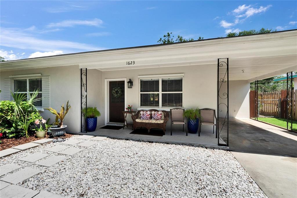A single-story house exterior features a gravel front yard, a covered porch, and a carport — 1623 SAN MATEO DRIVE, DUNEDIN, FL