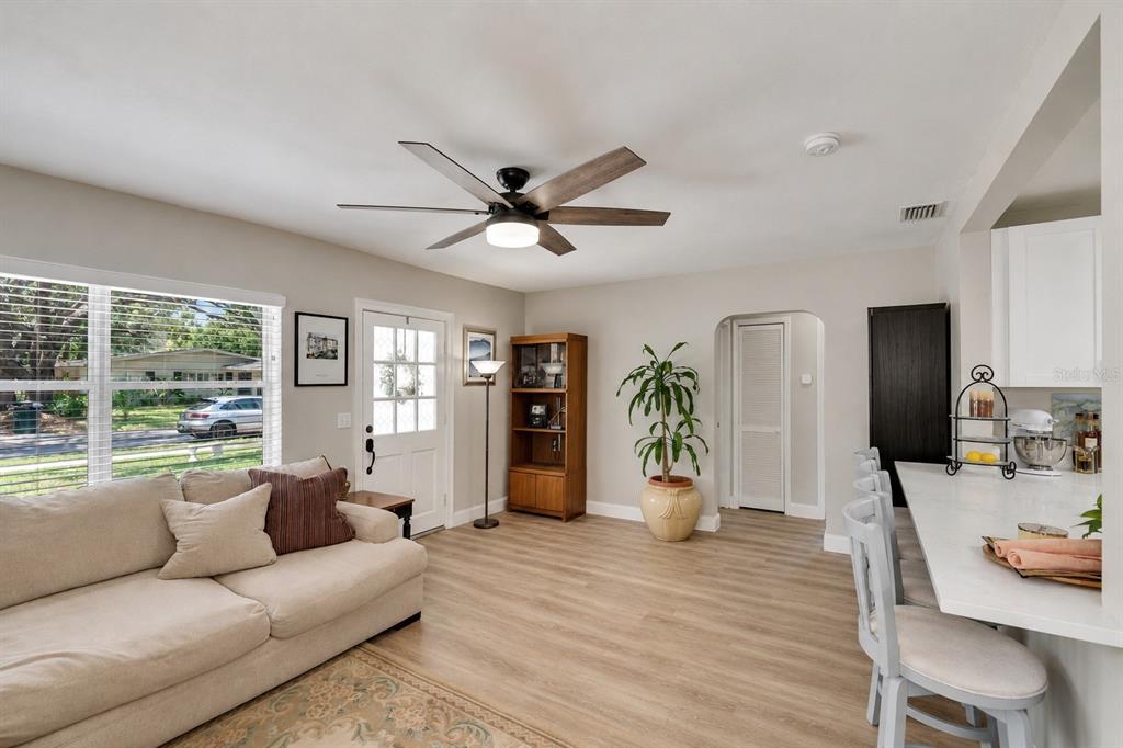 A living room with light wood flooring, a ceiling fan, a sofa, and a breakfast bar — 1623 SAN MATEO DRIVE, DUNEDIN, FL