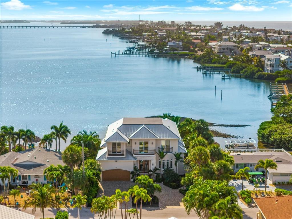 An aerial view of a multi-story waterfront home with a metal roof and palm trees — 511 BAYVIEW DRIVE, HOLMES BEACH, FL