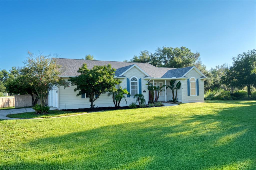 A single-story house with light siding, a shingled roof, and a large front lawn — 37015 WALDO DRIVE, DADE CITY, FL