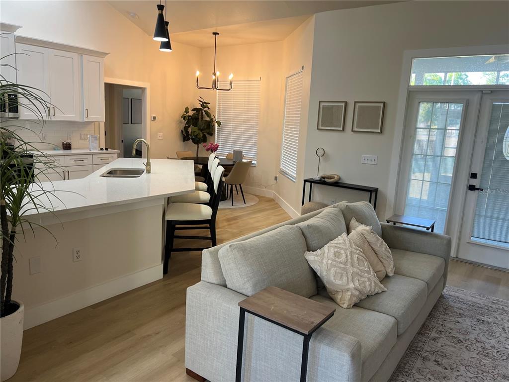An open-concept kitchen with a white island and dining area overlooks a living room — 37015 WALDO DRIVE, DADE CITY, FL