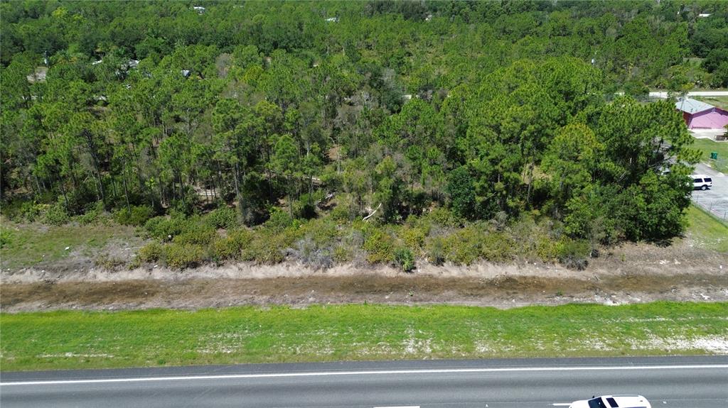 An aerial view shows a wooded lot bordering a highway and a drainage ditch — 12209 12215 12219 12225 TAMIAMI TRAIL, PUNTA GORDA, FL