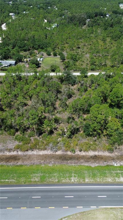 An aerial view shows a wooded lot situated between a residential road and a highway — 12209 12215 12219 12225 TAMIAMI TRAIL, PUNTA GORDA, FL