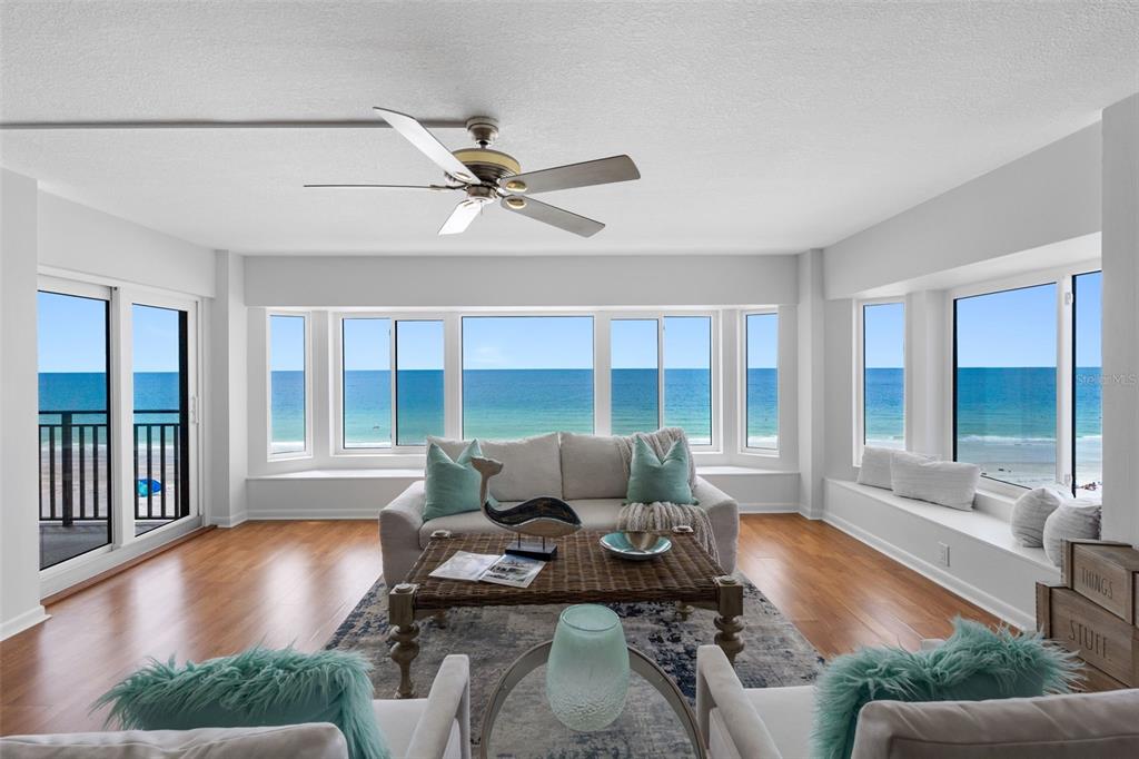 A bright living room features a sofa, coffee table, and large windows overlooking the ocean — 1310 GULF BOULEVARD UNIT 503, INDIAN ROCKS BEACH, FL