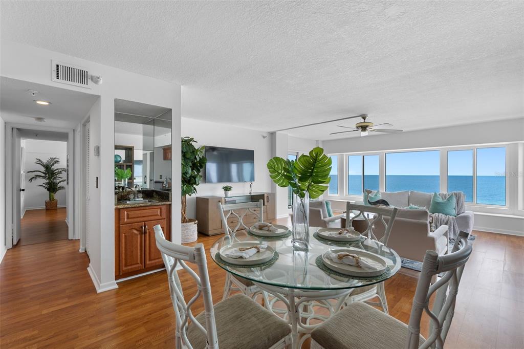 A dining area with a glass table and ocean view through large windows in a living room — 1310 GULF BOULEVARD UNIT 503, INDIAN ROCKS BEACH, FL