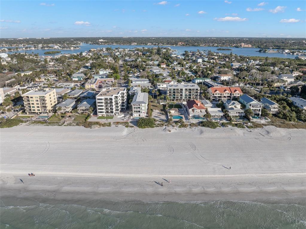 An aerial view shows a sandy beach fronting several multi-story apartment buildings and residential homes — 1306 GULF BOULEVARD, INDIAN ROCKS BEACH, FL